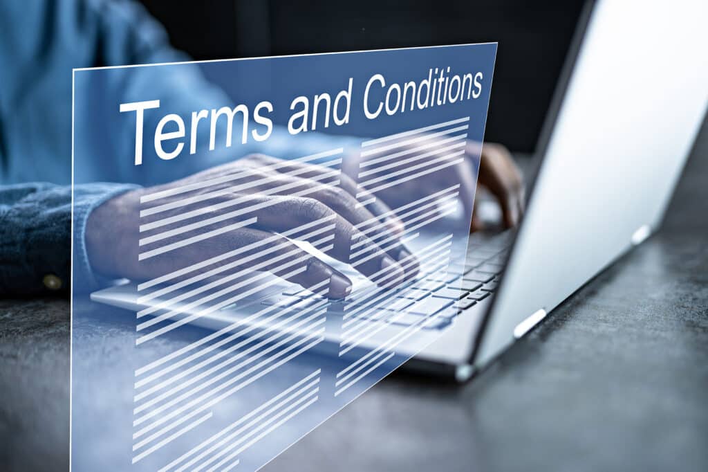 Person typing on laptop with floating terms and conditions