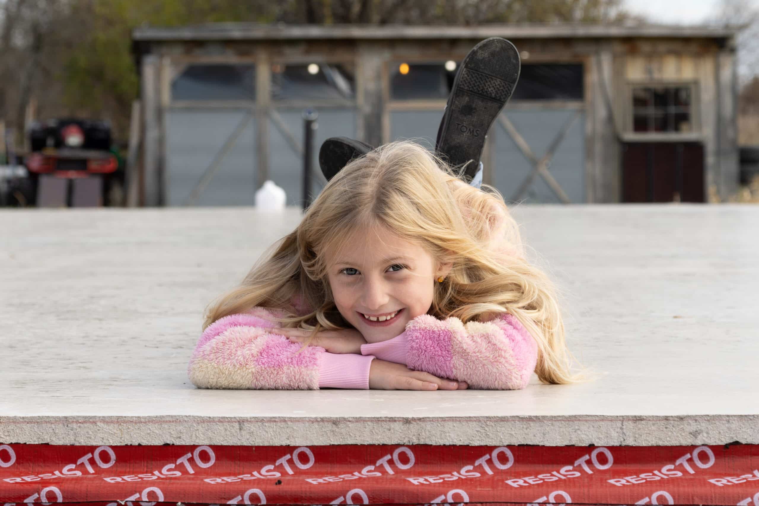 Girl in colourful sweater smiling while lying on a concrete slab