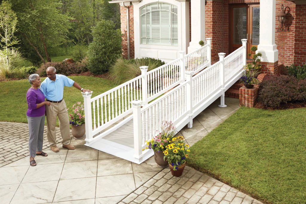 Couple examining a white accessible ramp leading to a brick house entrance