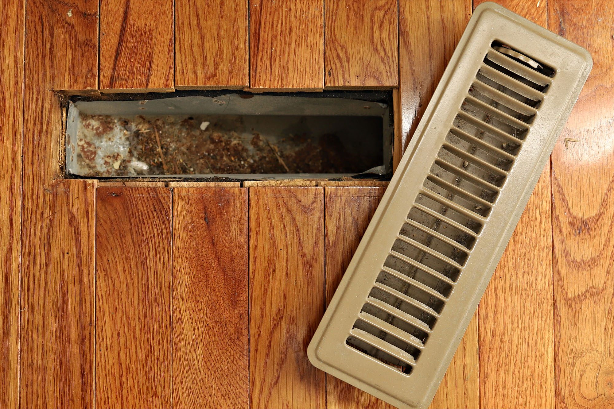 Open floor vent showing dirt and debris inside duct