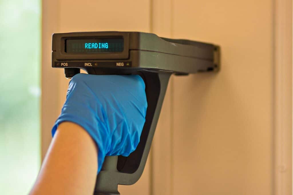 Person using a moisture meter on a wall for inspection