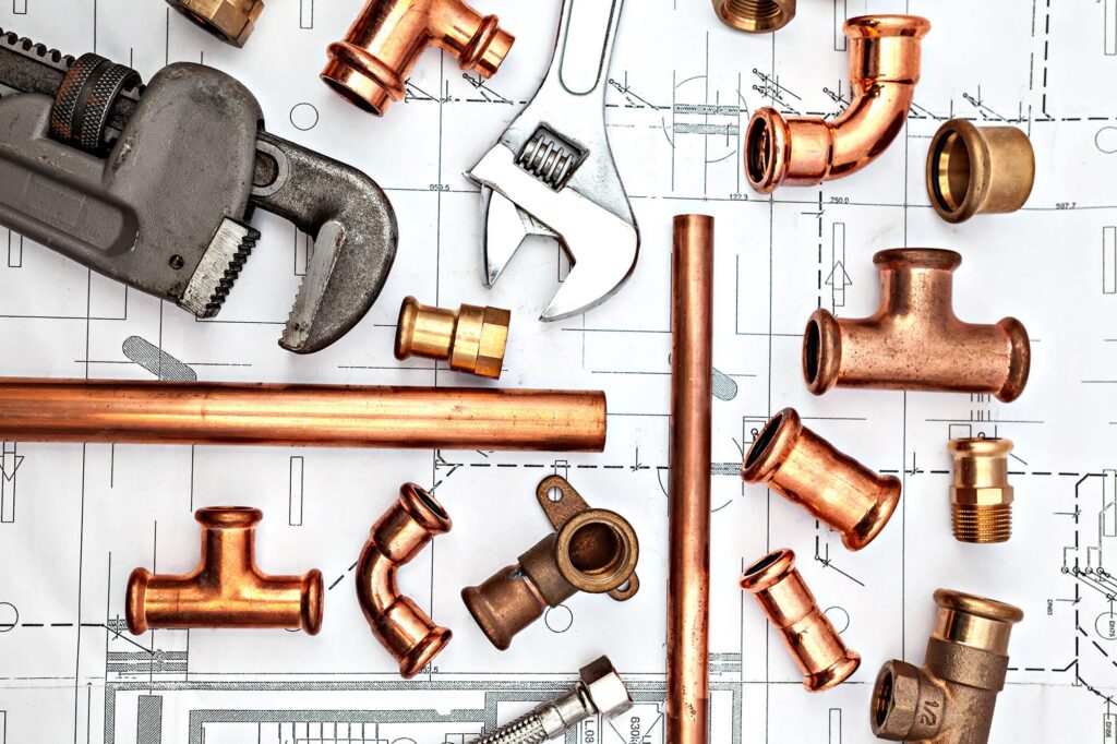 Plumbing tools and copper fittings on blueprint