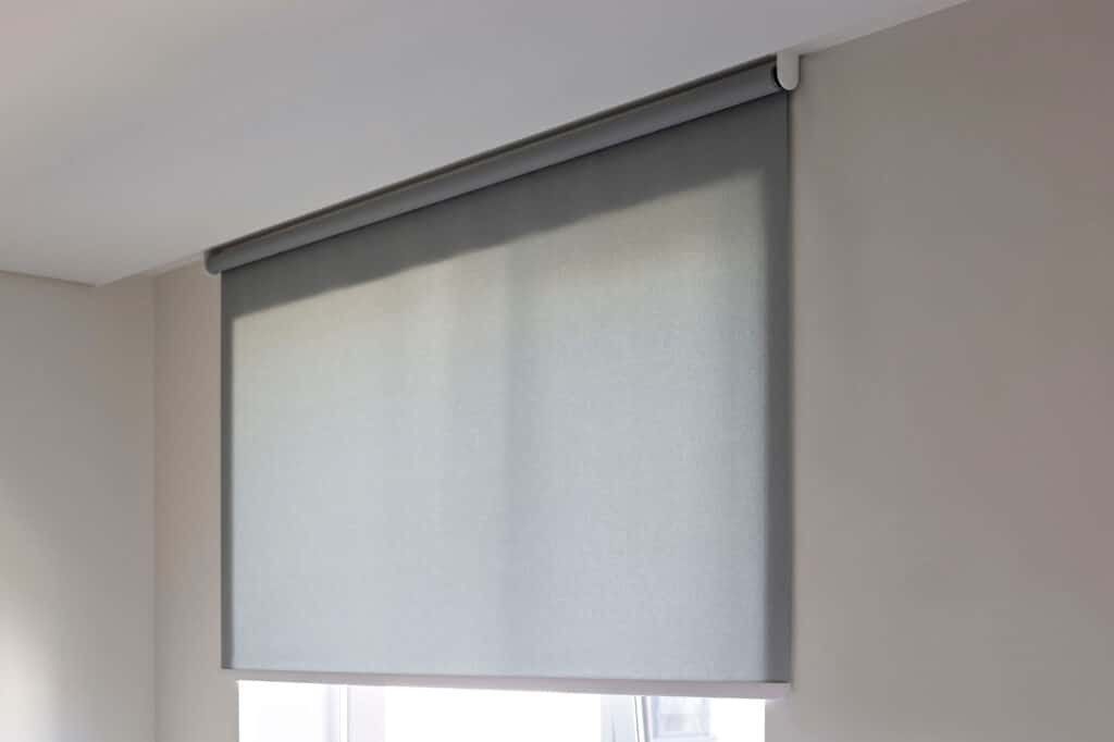 Grey roller blind on a window in minimalist room