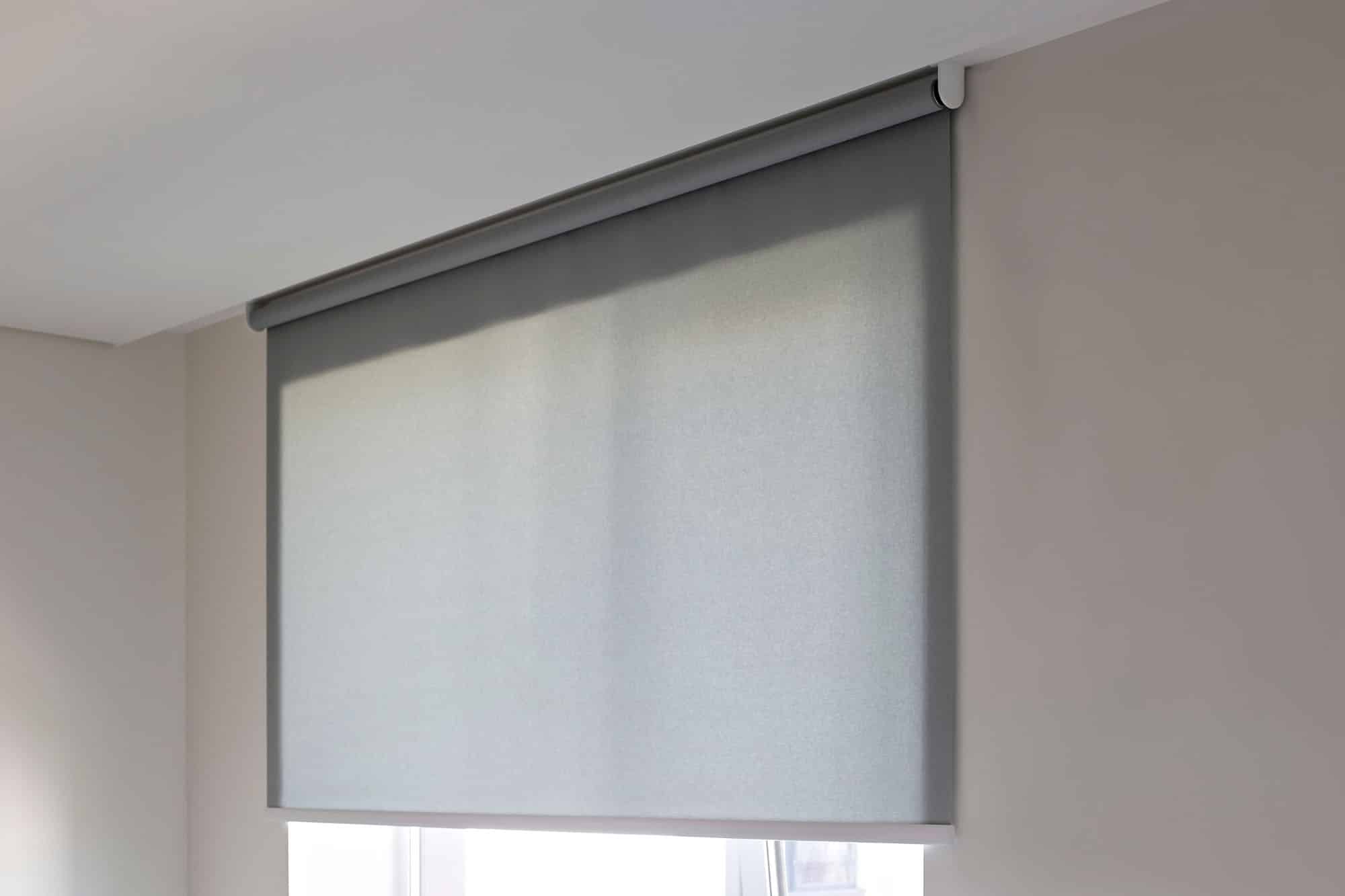 Grey roller blind on a window in minimalist room