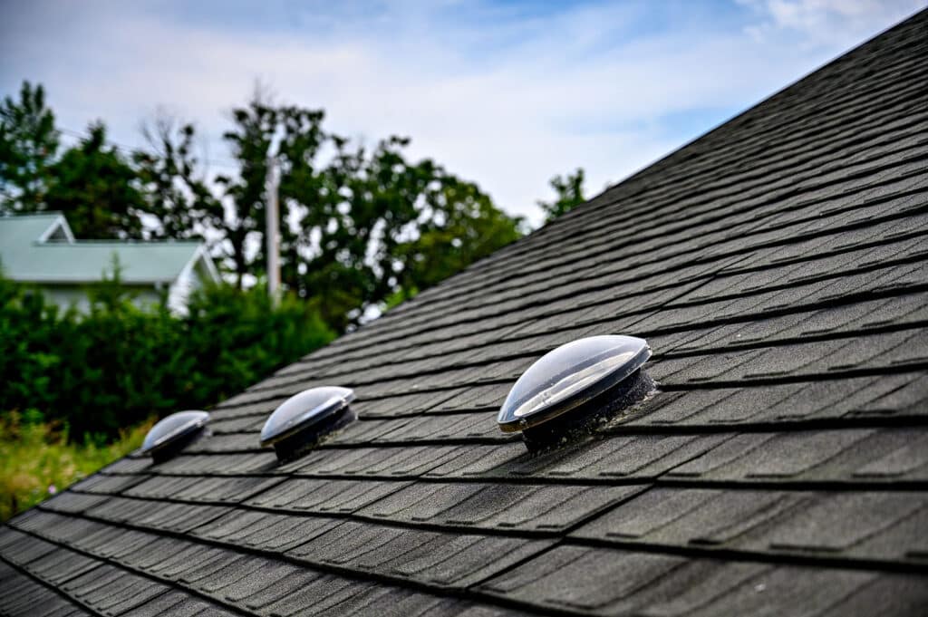 Three dome skylights on a grey shingle roof