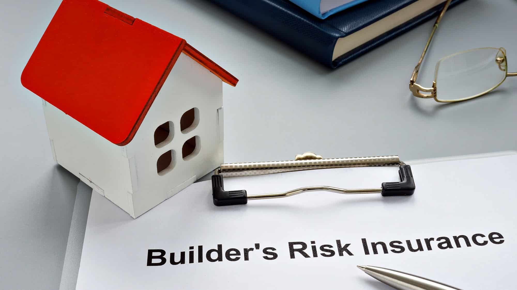 Model house and builder's risk insurance document on a desk