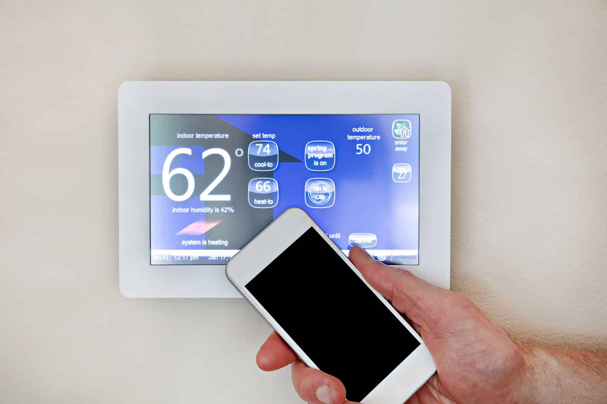Smart thermostat with smartphone displaying temperature settings