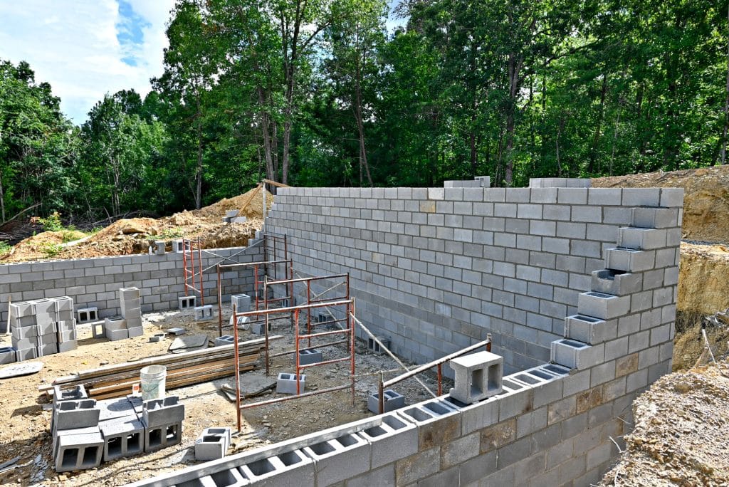 Construction site with partially built cinder block wall and scaffolding.