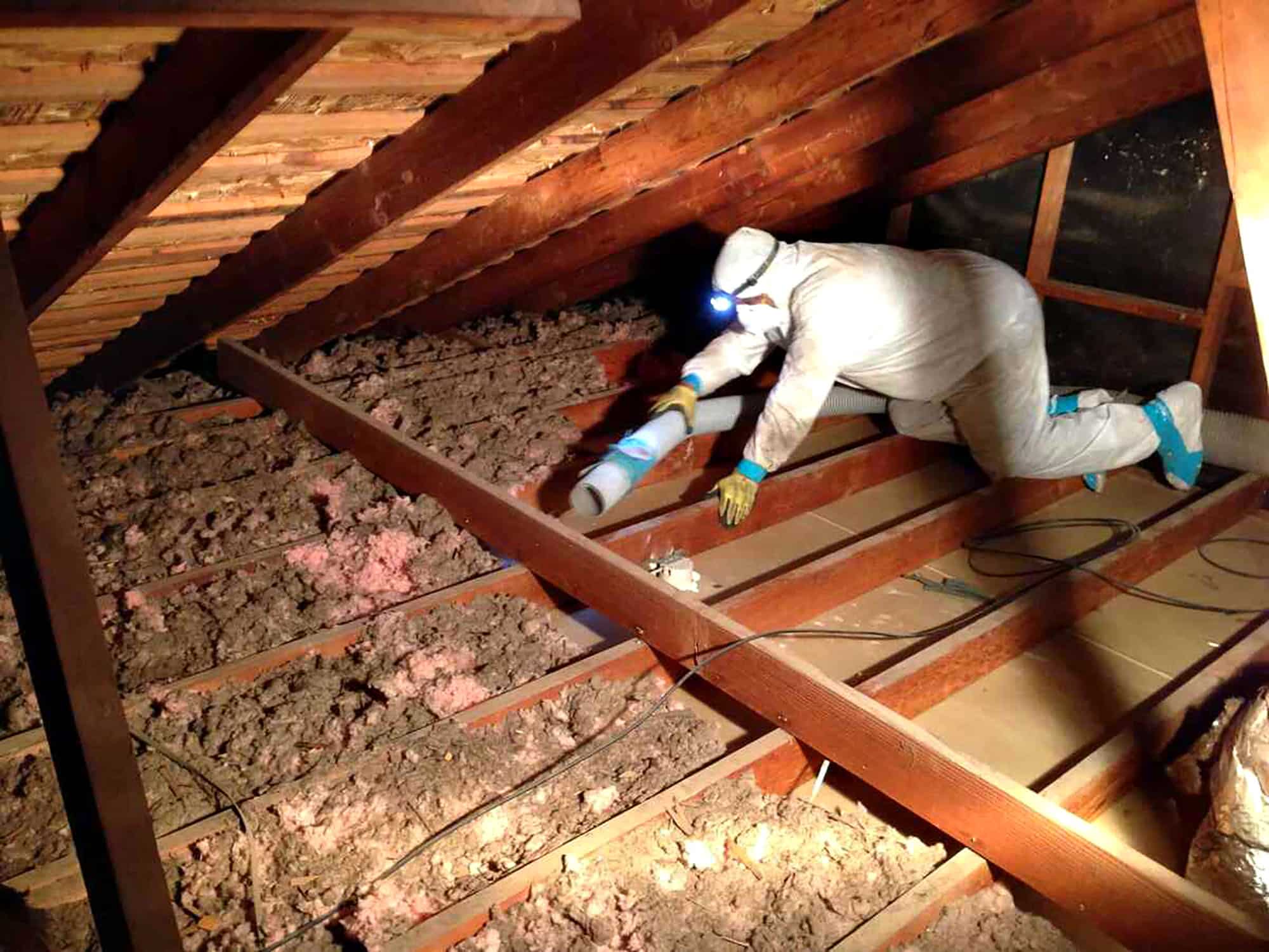 Attic insulation installation by worker in protective gear