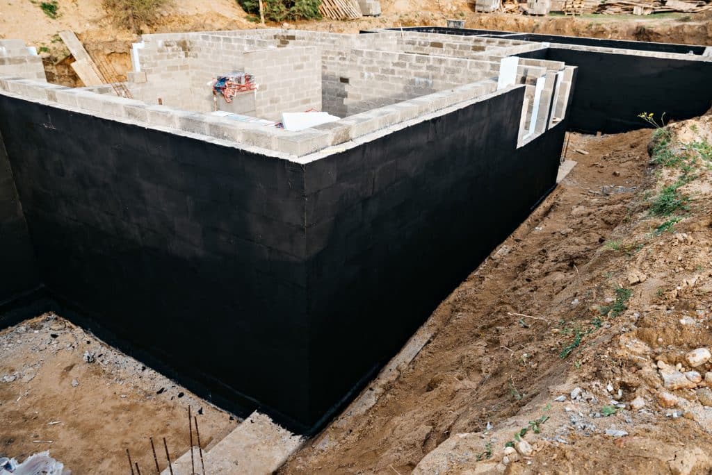 Waterproofed foundation of a house under construction with exposed concrete walls