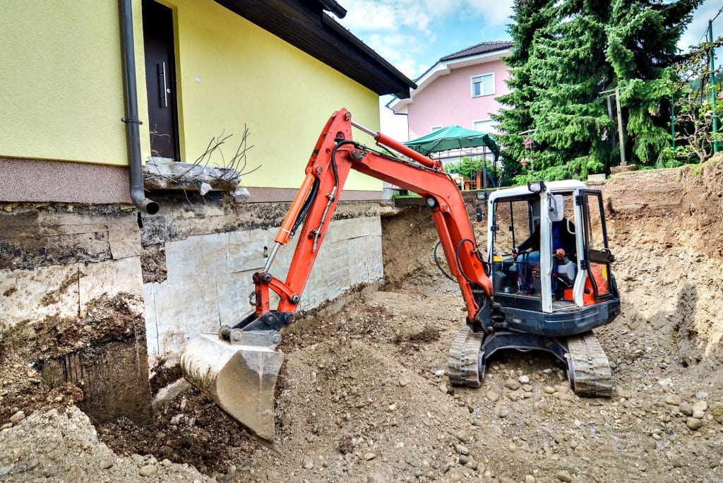 Mini excavator performing foundation excavation for house extension