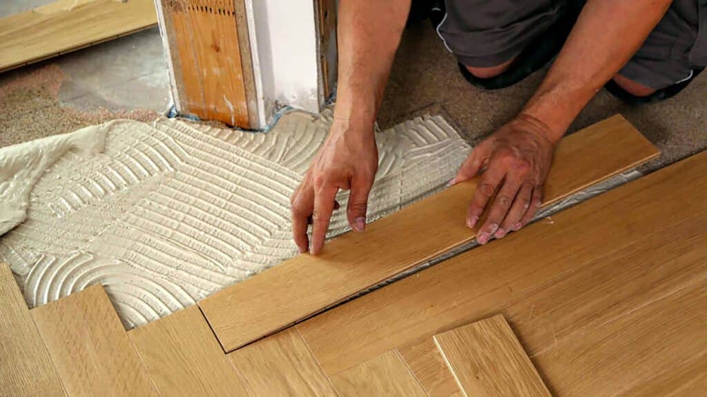 Person installing interlocking laminate flooring in a home