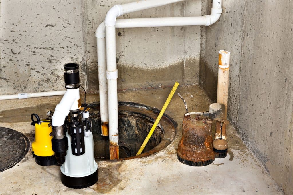 Basement sump pump installation with visible pipes and drainage