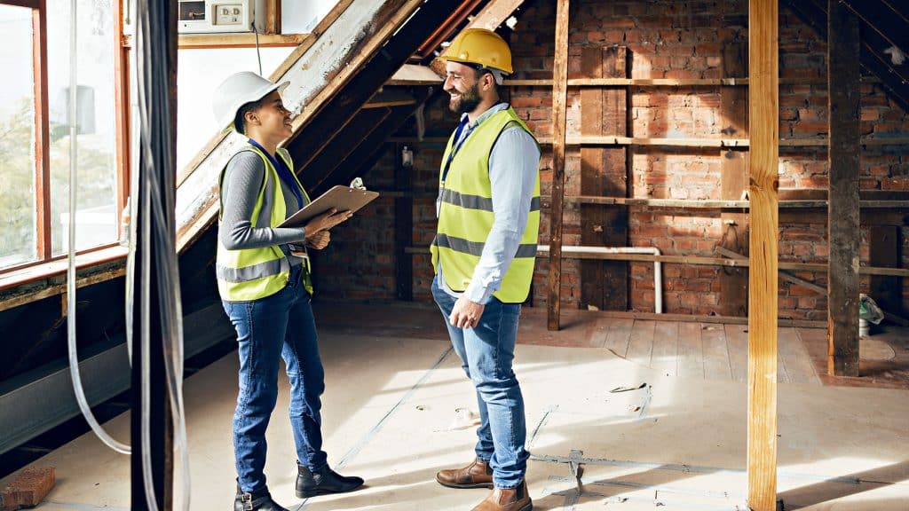 Construction professionals discussing renovation in unfinished attic space