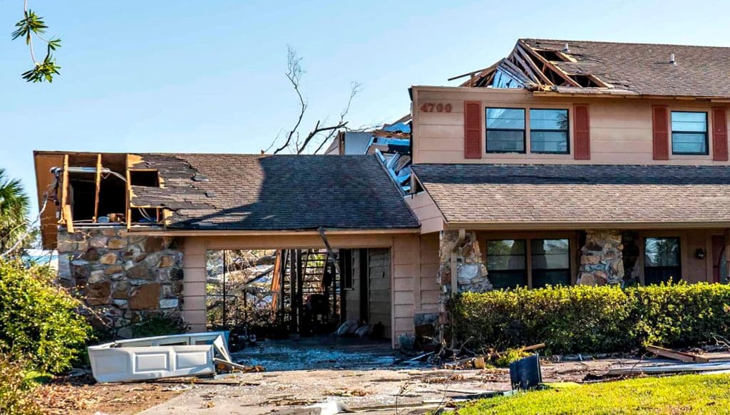 House with severe roof damage after a storm in a suburban neighbourhood