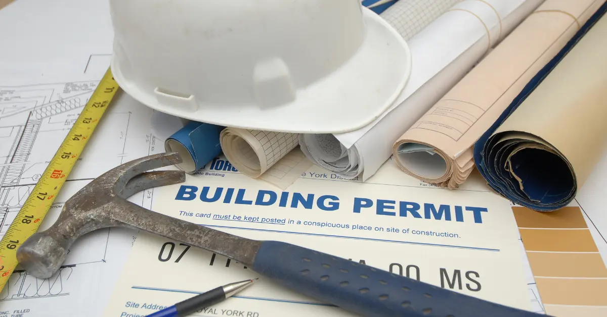Construction plans with hard hat, hammer, and building permit