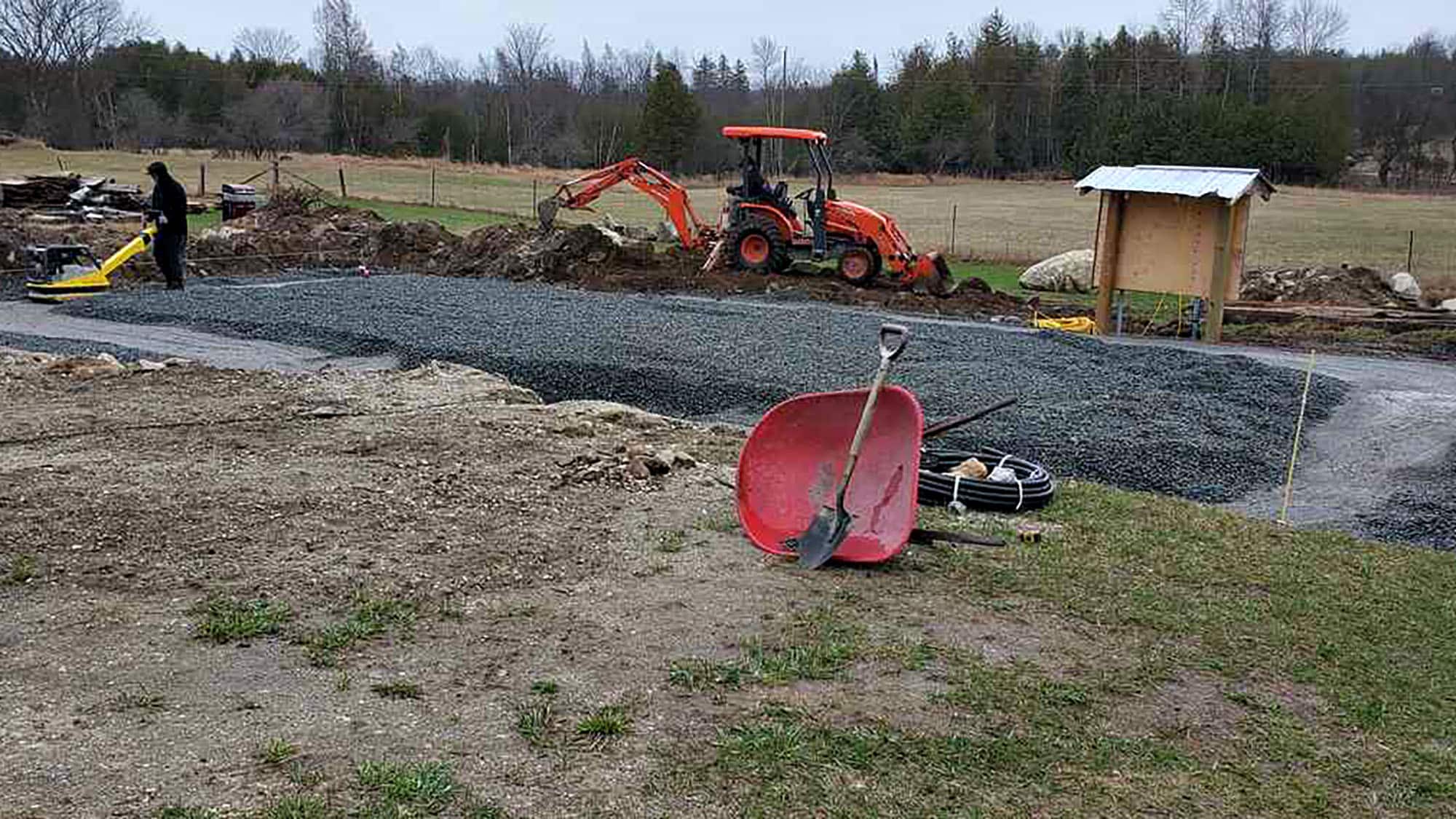 Construction site with tractor and gravel foundation near field