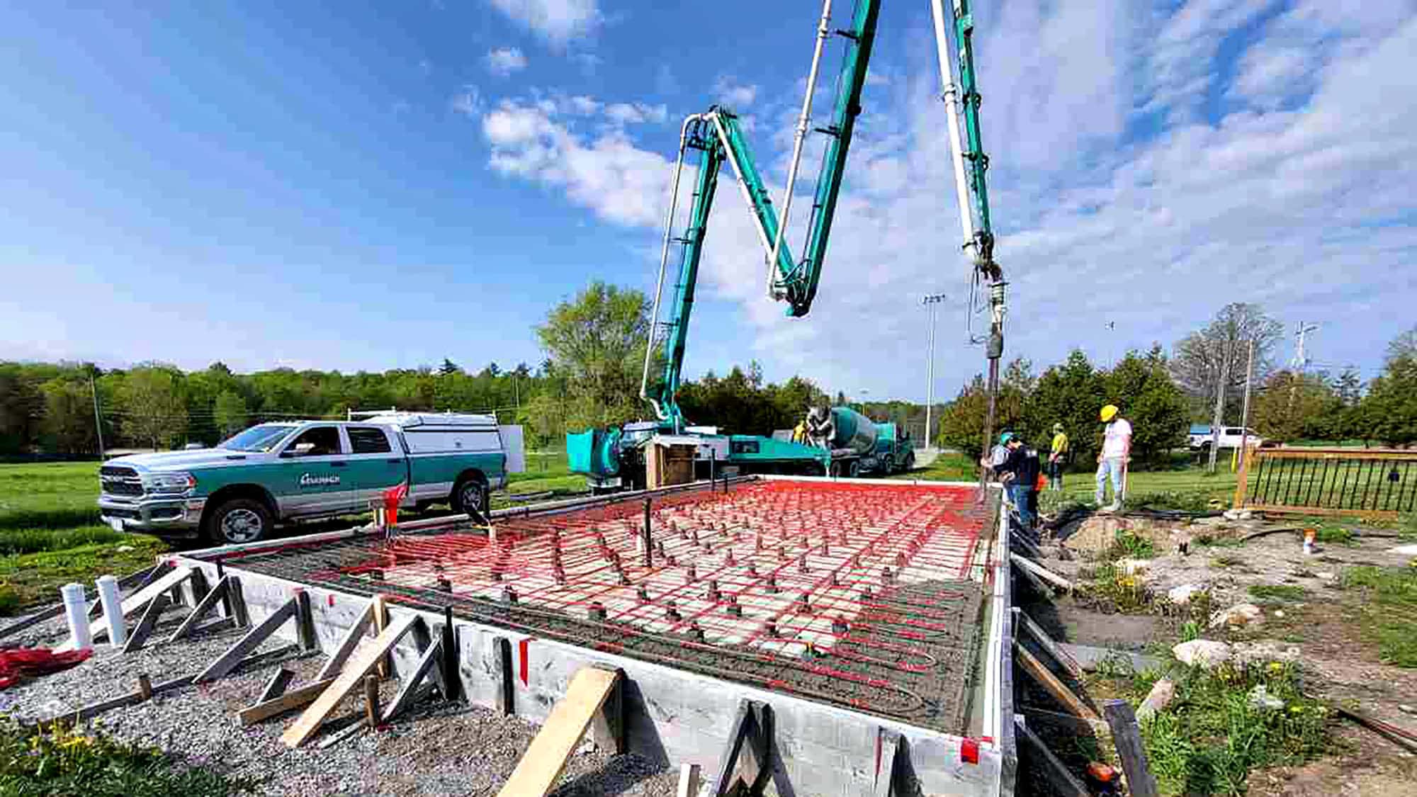 Workers pouring concrete foundation with pump truck at construction site