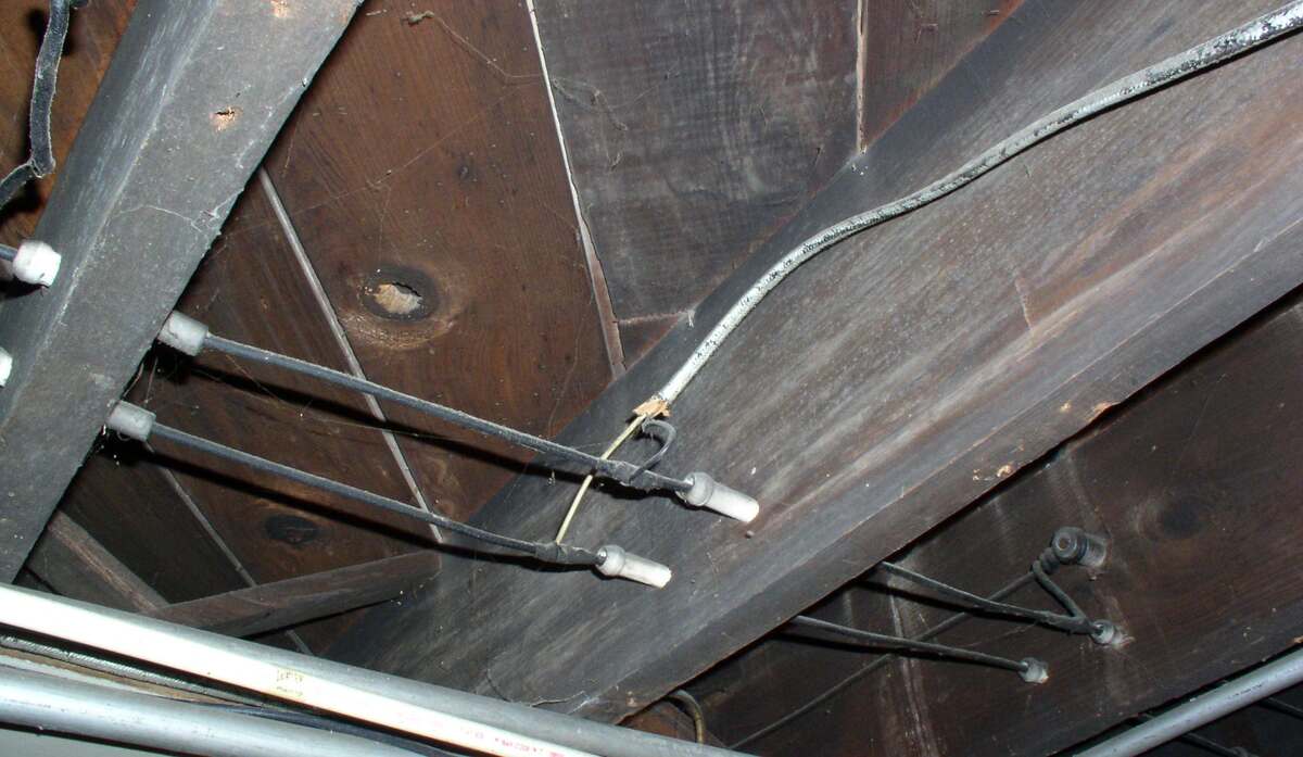 Old, frayed wiring on wooden ceiling beams