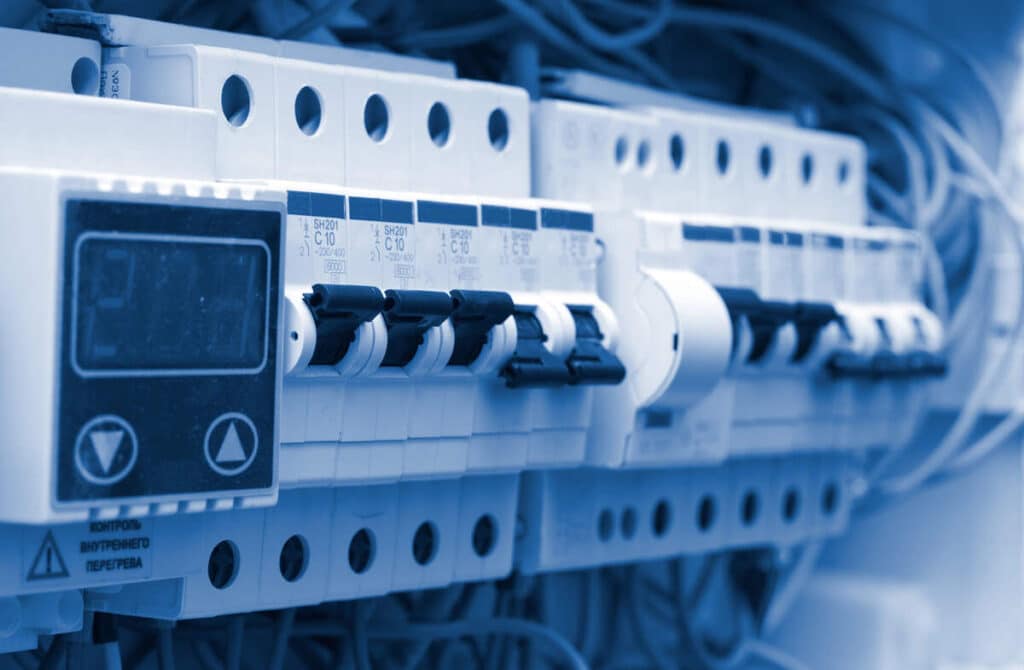 Close-up of electrical circuit breakers and wiring in a blue-lit panel