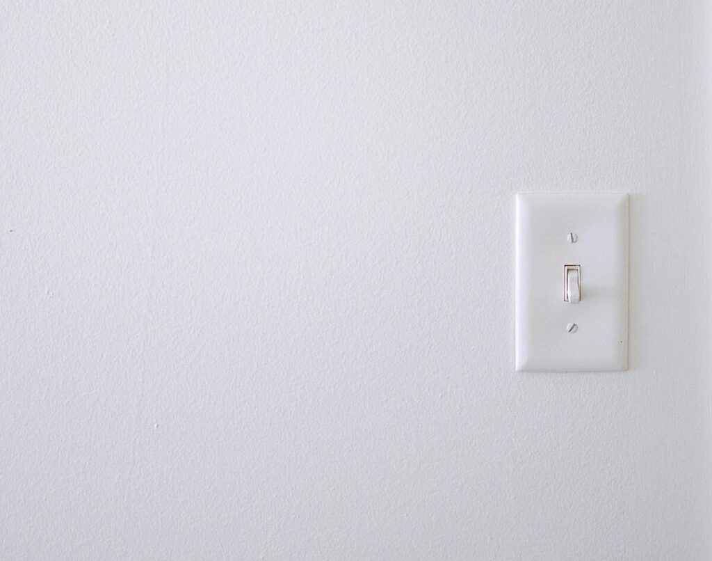Minimalist image of a white wall with a light switch