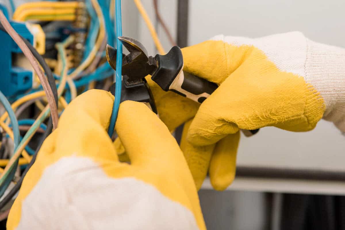 Electrician using wire cutters on electrical wires