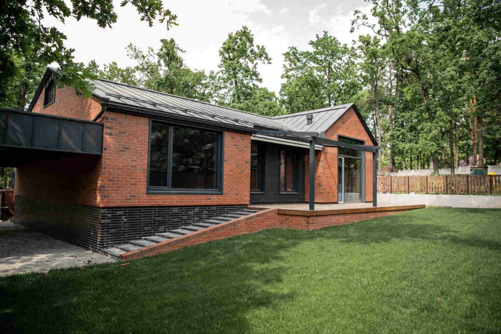 Modern brick house with large windows and sloped garden