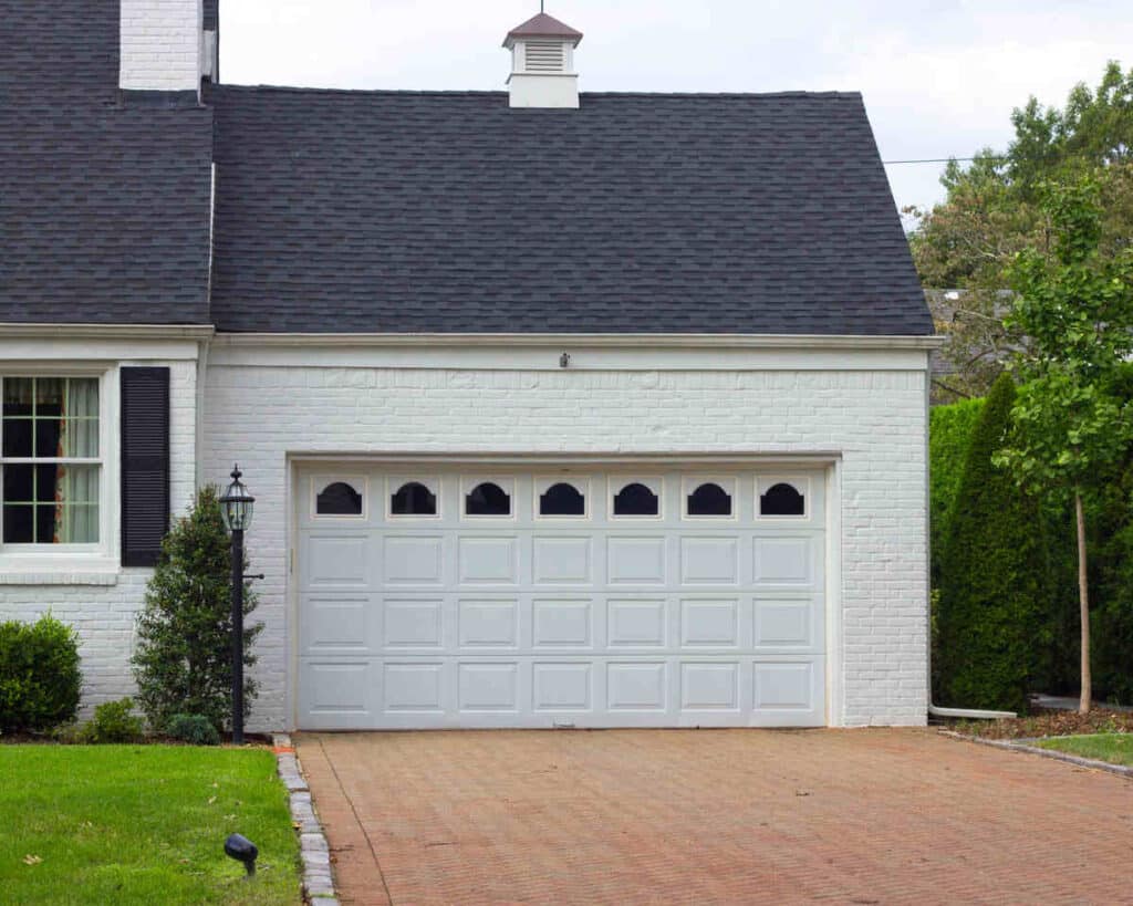 White brick house with black shutters and two-car garage