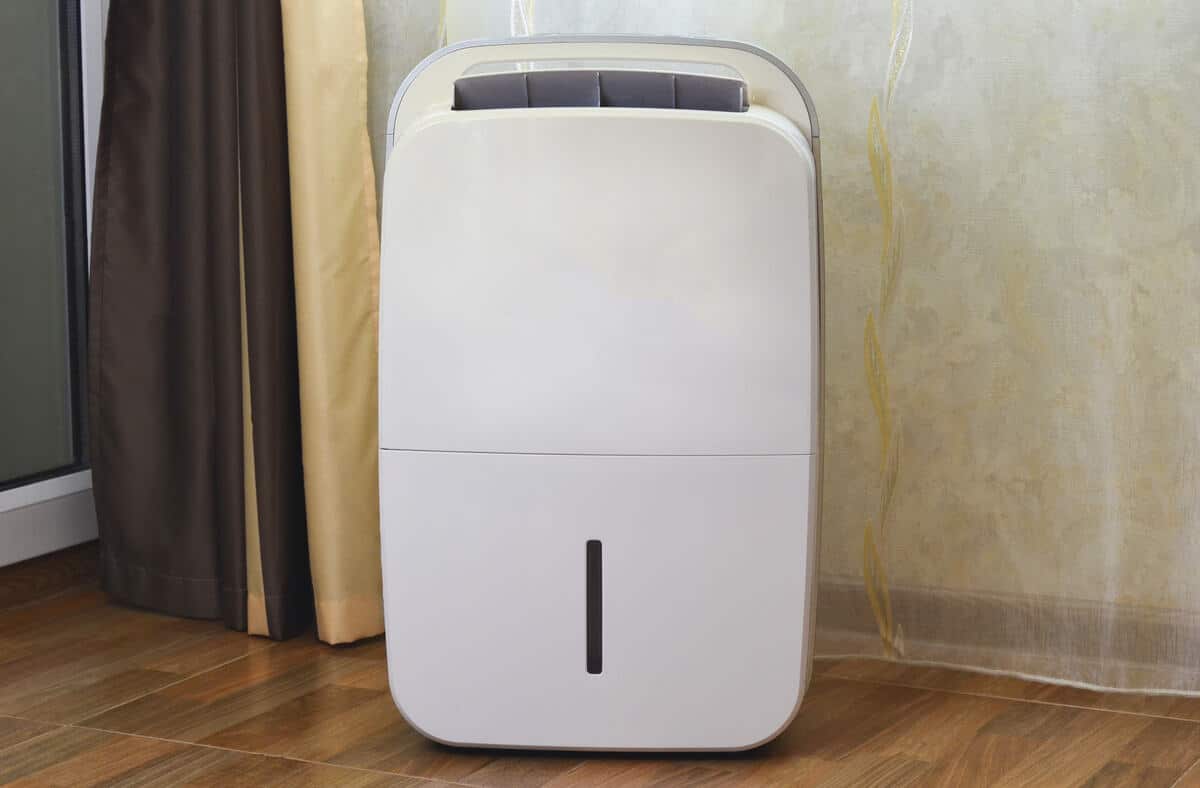 Modern portable dehumidifier in room with wood flooring