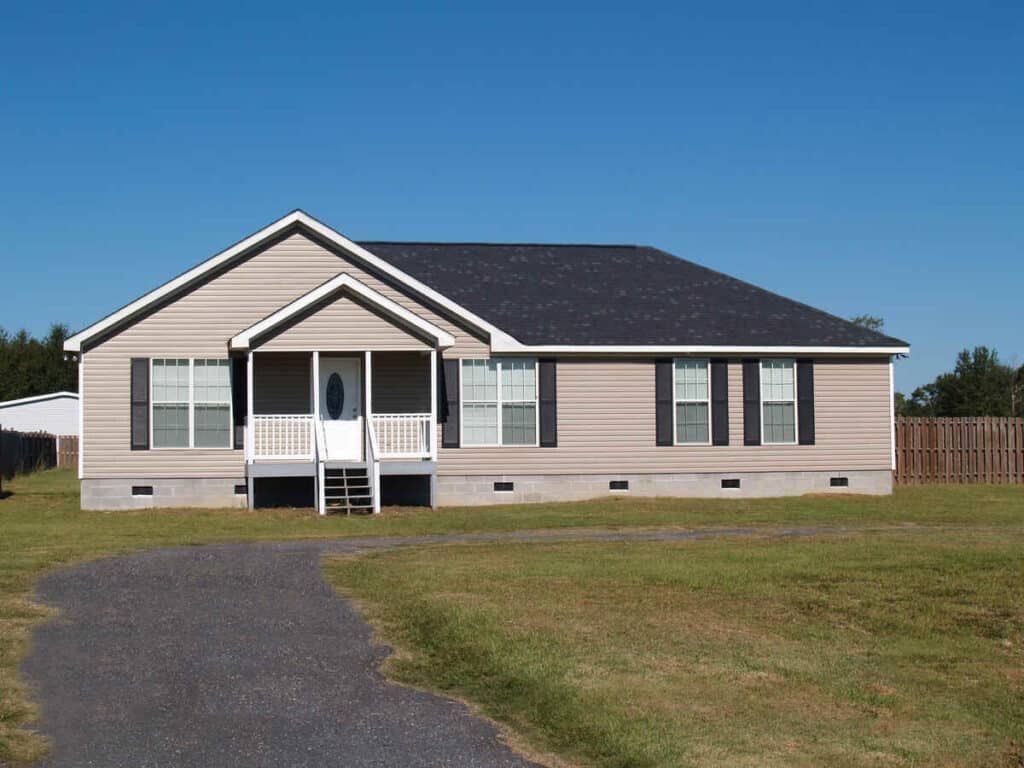 Single-storey tan siding house with black rooftop and front porch