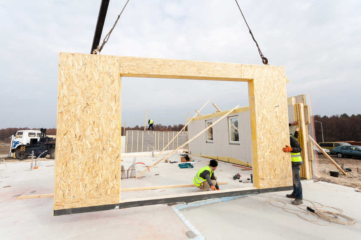 Workers installing prefabricated wall panels at a construction site