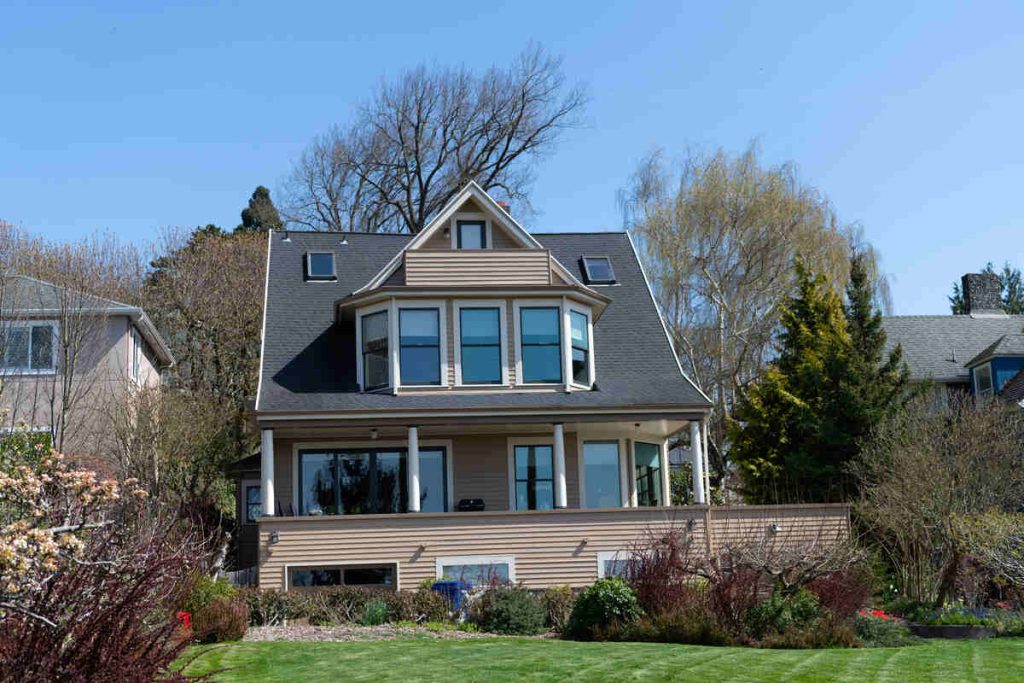 Two-storey house with attic, surrounded by trees, under a clear sky