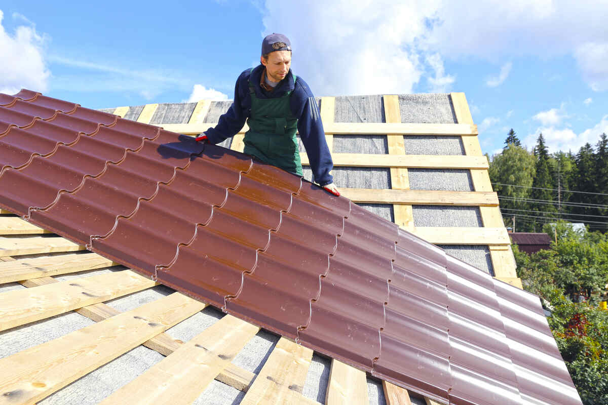 Roofer installing metal shingles on wooden framework