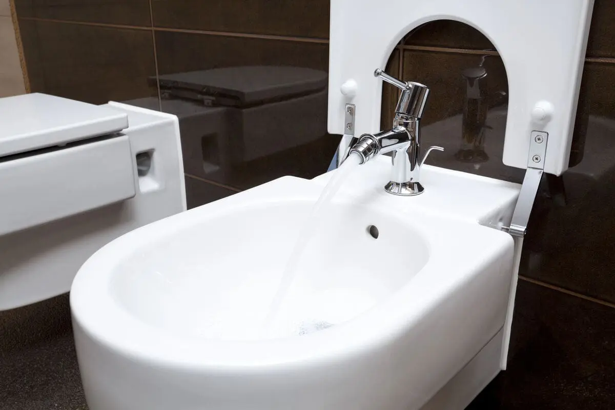 Modern white bidet with a silver faucet in a bathroom