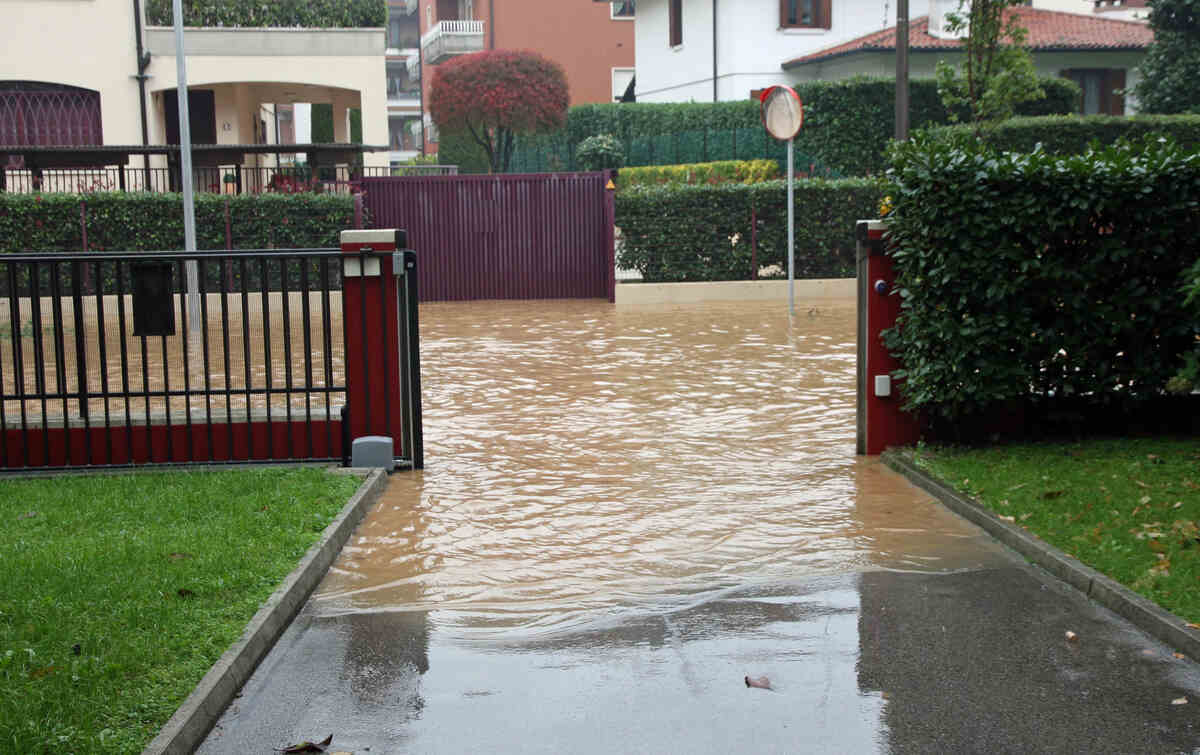 Flooded residential street with waterlogged driveways after heavy rain