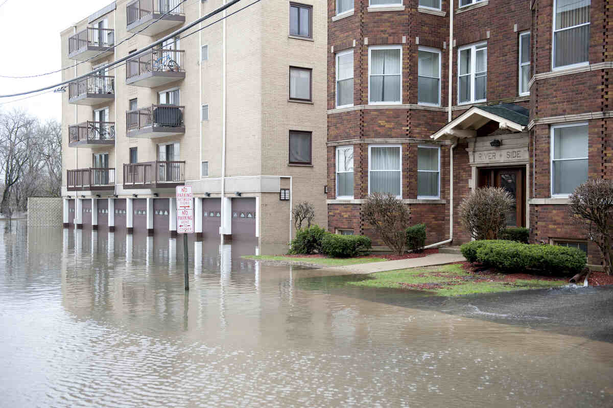 Flooded street beside a residential apartment building in a suburban area