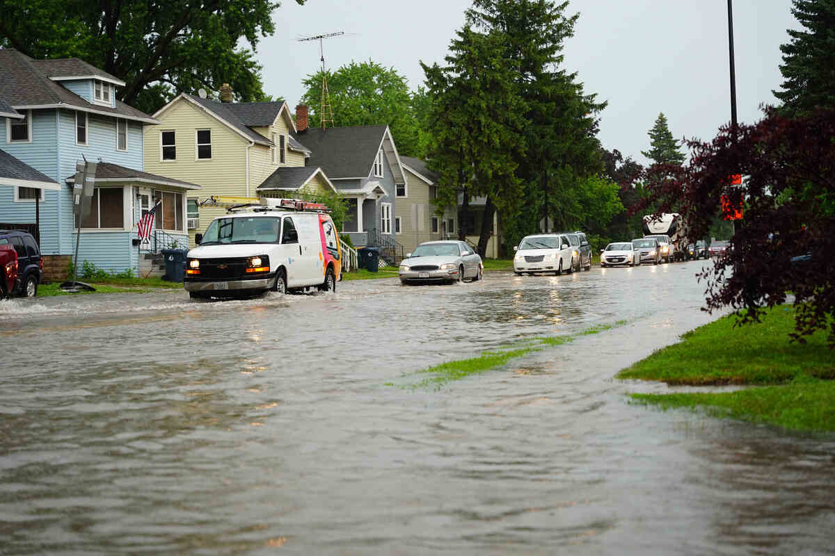 Flooded neighbourhood street with cars and emergency vehicle