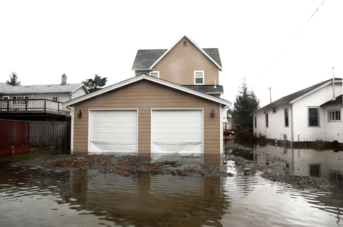 Flooded residential street with submerged garages and brown house