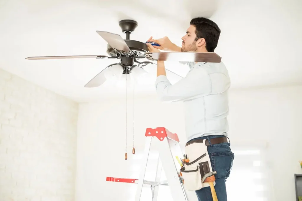 Electrician installing ceiling fan in modern home