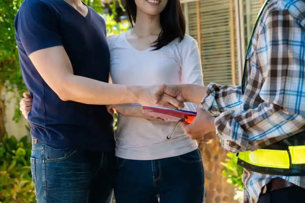 Couple signing agreement with contractor outdoors