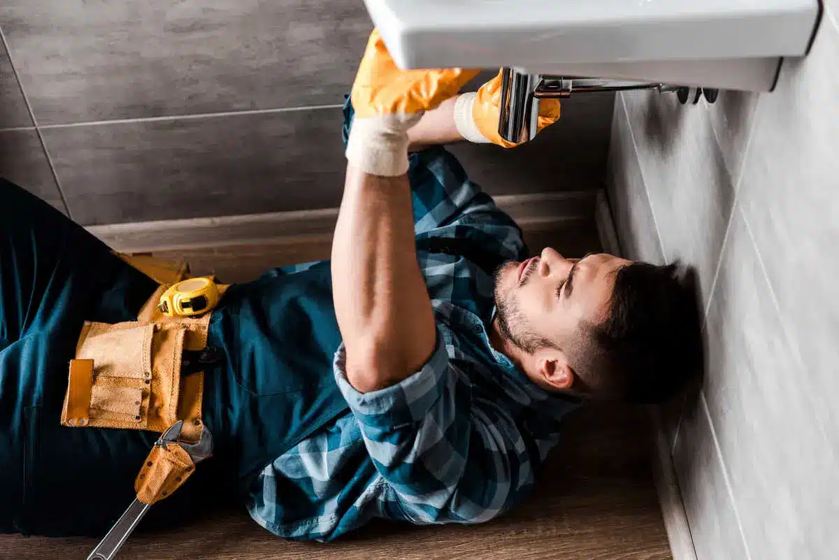 Plumber repairing sink pipes in bathroom