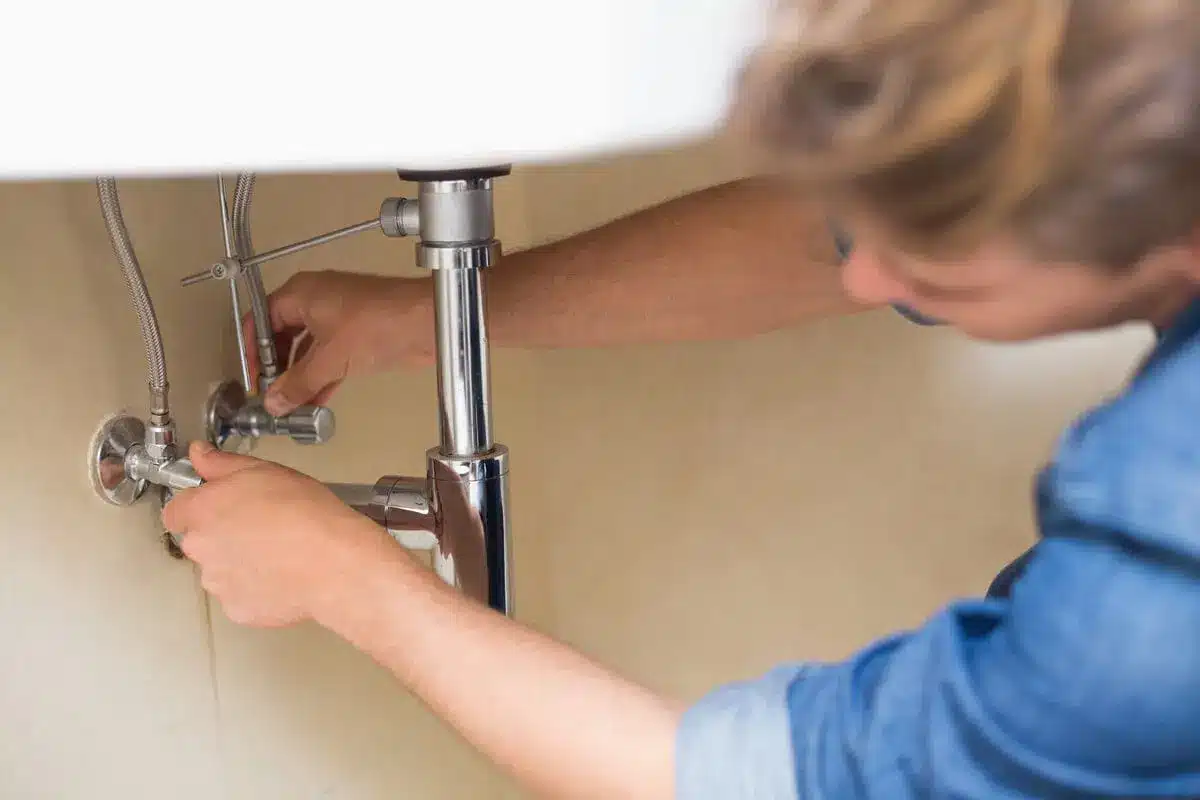 Plumber fixing sink pipes in residential home plumbing repair