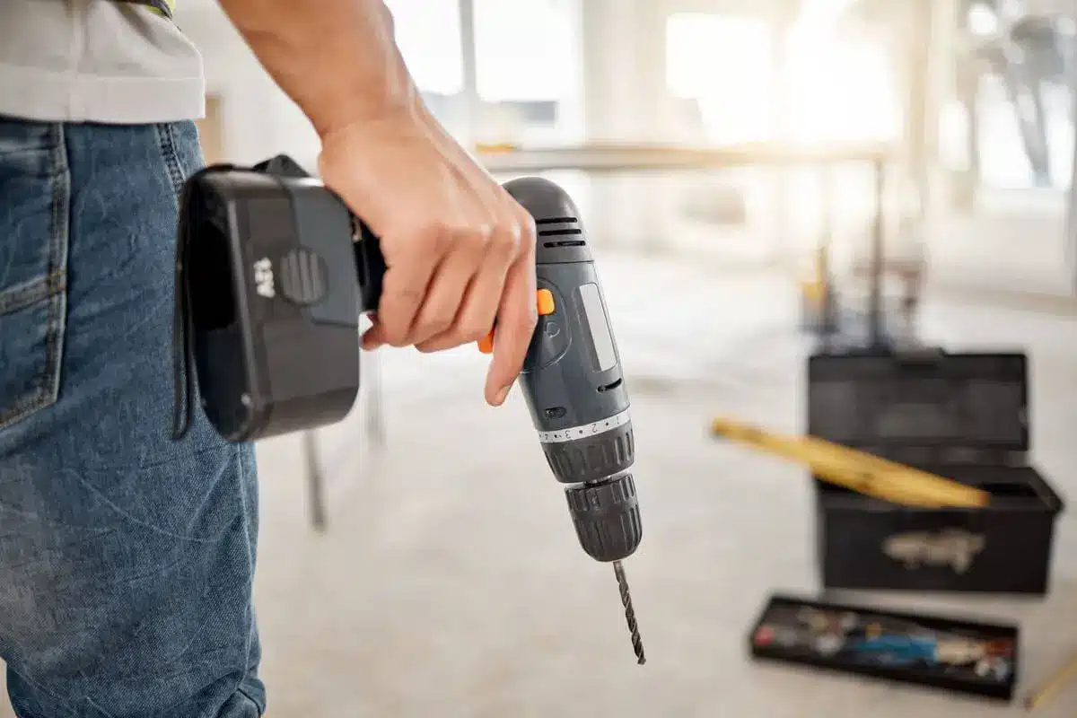 Person holding a cordless power drill in a home renovation setting