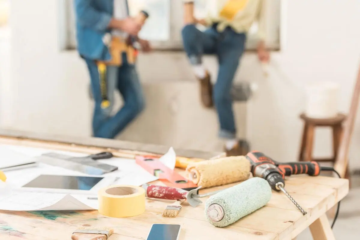 Home renovation tools on table with two people in background