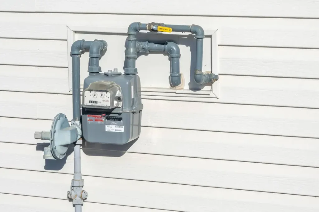Natural gas meter on residential house exterior with pipes