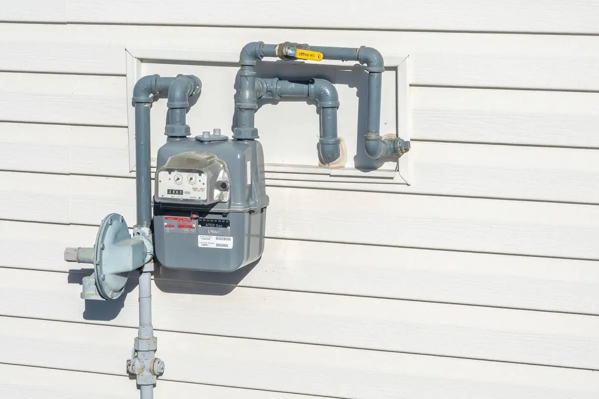Natural gas meter on residential house exterior with pipes