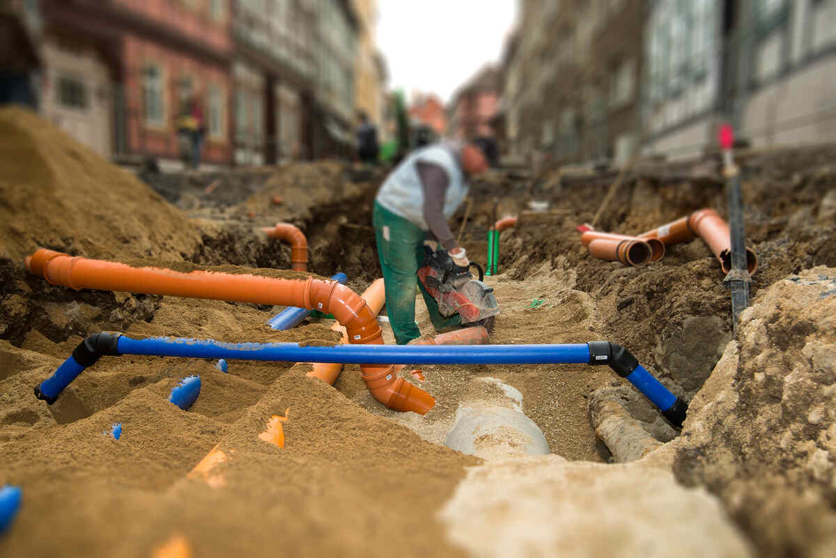 Construction worker installing underground water pipes on a city street