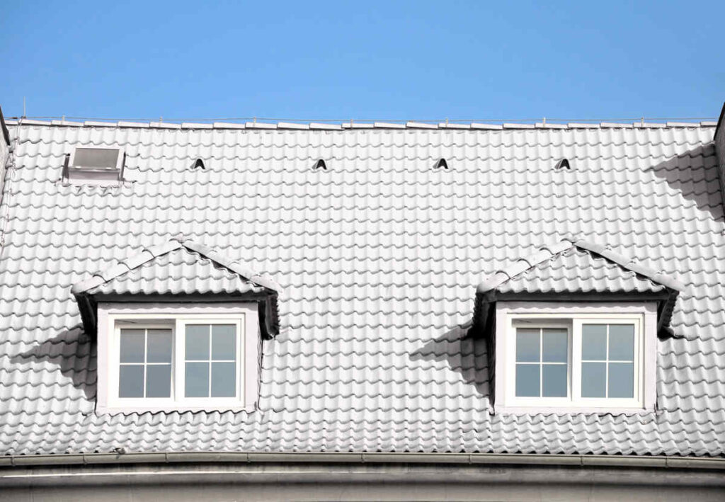 White tiled roof with two dormer windows under clear sky
