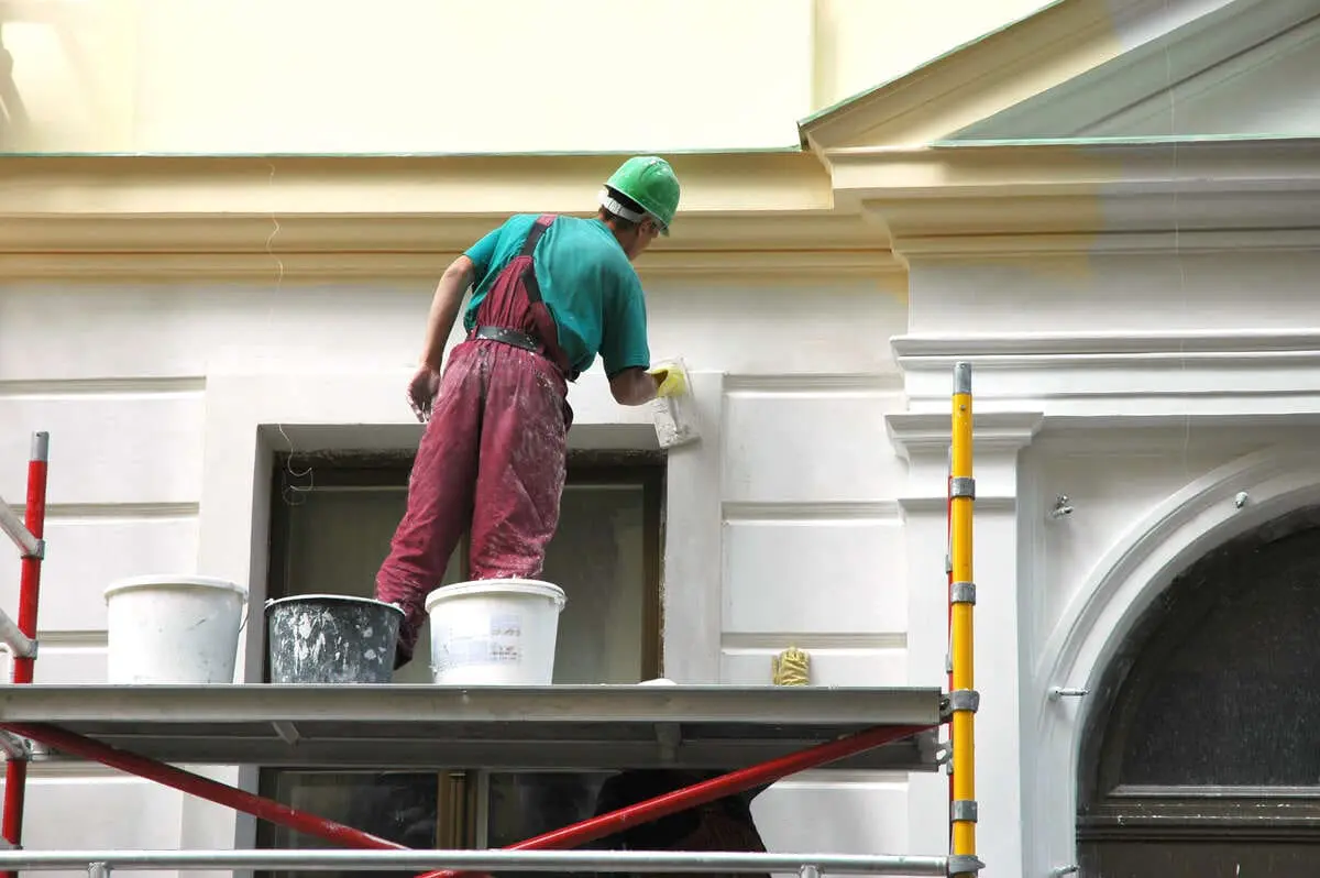 Construction worker painting exterior building wall