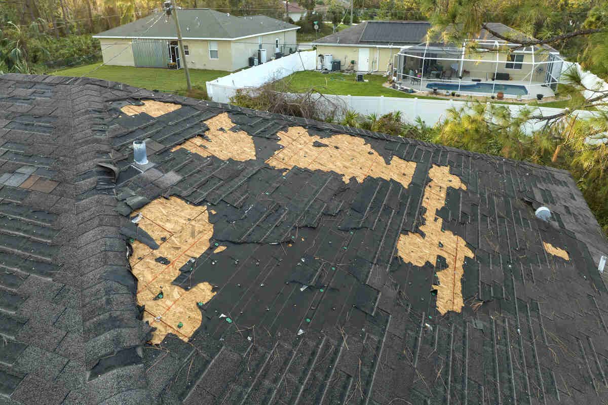 Damaged roof with missing shingles after storm in residential area